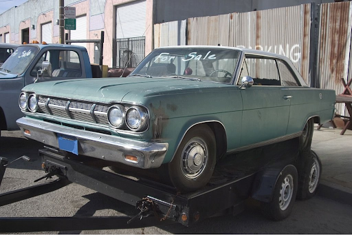 Classic car on a trailer with "For Sale" sign